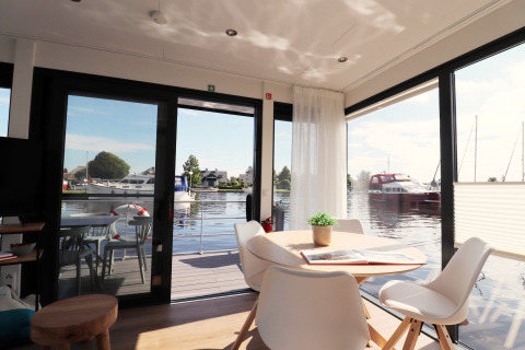 Intérieur lumineux et moderne du houseboat «Refugio» avec vue sur l’eau et les bateaux, Pays-Bas.
