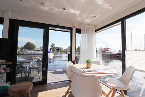 Helles, modernes Wohnzimmer auf Hausboot „Refugio“ mit Blick auf Wasser und Boote, Niederlande.