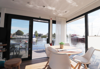 Intérieur lumineux et moderne du houseboat «Refugio» avec vue sur l’eau et les bateaux, Pays-Bas.