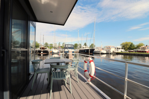 Vue depuis la terrasse de Houseboat Refugio avec table, chaises et marina aux Pays-Bas