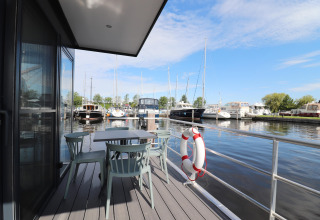 Blick von der Houseboat Refugio Terrasse mit Tisch, Stühlen und Blick auf Boote im Hafen in den Niederlanden