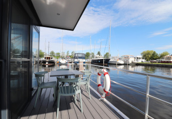 Vista dal ponte di Houseboat Refugio con tavolo, sedie e barche nel porto nei Paesi Bassi
