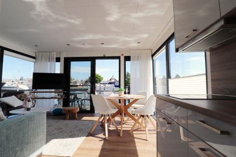 Intérieur moderne et lumineux de la péniche «Refugio» aux Pays-Bas avec vue sur la marina à travers de grandes fenêtres.