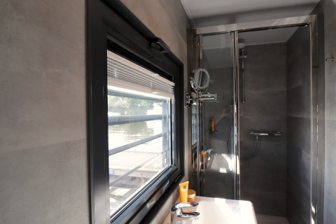 Modernes Badezimmer auf dem Hausboot 'Refugio' in den Niederlanden mit Fenster und Dusche.