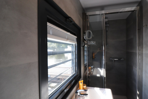 Bagno moderno sulla houseboat 'Refugio' nei Paesi Bassi con finestra, lavandino e doccia.