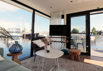Wohnbereich auf dem Hausboot 'Refugio' in den Niederlanden mit Blick auf Yachthafen und Wasser.