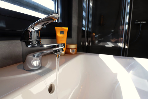 Robinet moderne avec eau courante sur Houseboat Refugio aux Pays-Bas, lumière du soleil entrant par la fenêtre.