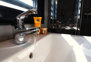 Robinet moderne avec eau courante sur Houseboat Refugio aux Pays-Bas, lumière du soleil entrant par la fenêtre.