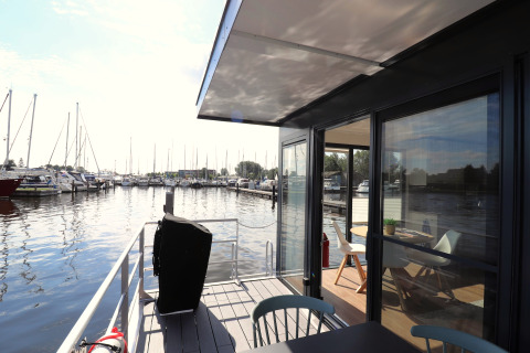 Blick von der Terrasse des Hausboots Refugio in den Niederlanden mit Hafen und moderner Einrichtung.