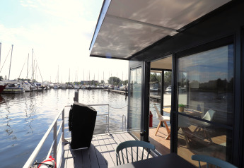 View from the deck of Houseboat Refugio in the Netherlands, overlooking a marina and modern interior.