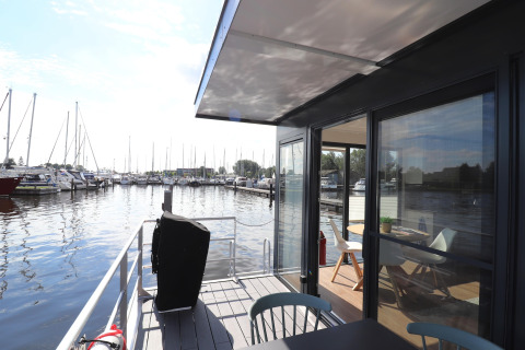 Vista dal ponte della houseboat Refugio nei Paesi Bassi, con porto turistico e arredo moderno.