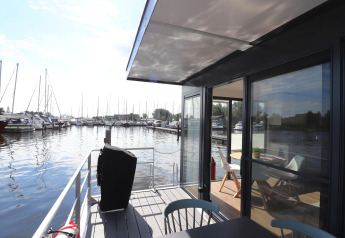 Vista dal ponte della houseboat Refugio nei Paesi Bassi, con porto turistico e arredo moderno.