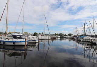 Zicht vanop woonboot 'Refugio' in Nederland met zeilboten aangemeerd in een stille jachthaven.
