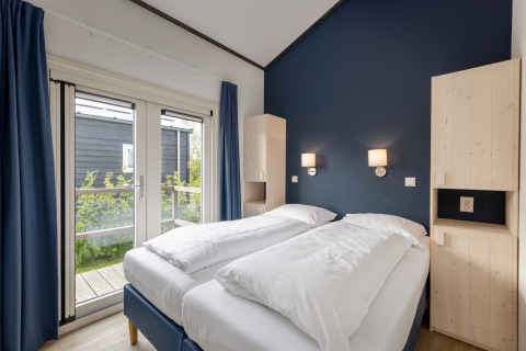 Luminoso dormitorio en el chalet Water park Terkaple 2, Países Bajos, con pared azul y camas individuales.