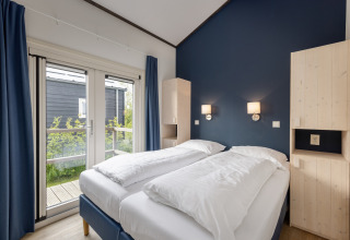 Helles Schlafzimmer im Water park Terkaple 2 Chalet in den Niederlanden mit blauem Wandakzent.