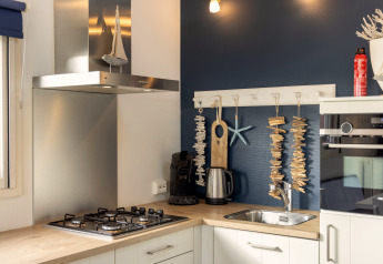 Moderne keuken in Water park «Terkaple 2» met gasfornuis, wastafel en maritieme decoratie aan de muur.