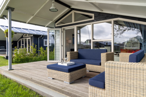 Terrasse extérieure avec meubles en osier et coussins bleus au chalet Water park « Terkaple 2 » aux Pays-Bas.