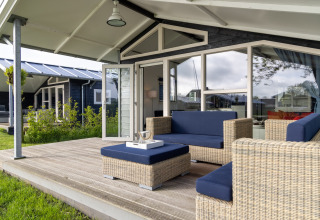 Terrasse extérieure avec meubles en osier et coussins bleus au chalet Water park « Terkaple 2 » aux Pays-Bas.