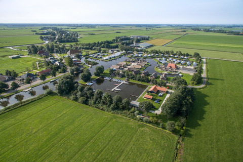 Luftaufnahme eines Chaletparks mit Jachthafen, grünen Feldern und ruhiger ländlicher Umgebung.