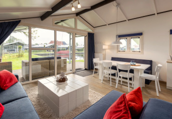 Bright chalet living and dining room with garden view, at Water park Terkaple 2, Netherlands.