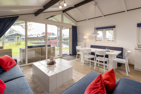 Helles Chalet-Wohnzimmer mit Essbereich und Ausblick auf Garten im Water park Terkaple 2, Niederlande.