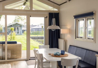 Bright, modern dining area inside a chalet at Water park 'Terkaple 2', Netherlands, overlooking garden.