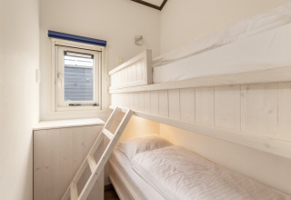 Chambre lumineuse avec lits superposés, panneaux en bois et fenêtre au chalet Water park «Terkaple 2», Pays-Bas.