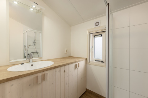 Bagno luminoso con piano in legno, lavabo, specchio e doccia al Water park Terkaple 2, Paesi Bassi.