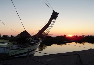 Foto eines Bootes an einem Chalet, festgemacht an einem ruhigen See bei Sonnenuntergang und Spiegelungen.