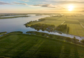 Luftfoto af solopgang over grønne marker og vand ved Water park Terkaple 2, Holland.