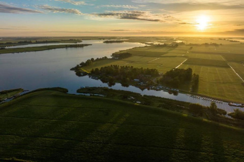 Vista aérea del amanecer sobre campos y agua en Water park Terkaple 2, Países Bajos.