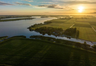 Luftfoto af solopgang over grønne marker og vand ved Water park Terkaple 2, Holland.