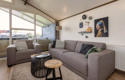 Woonkamer in chalet Water park Terkaple 1 in Nederland met moderne sofa's, decor en groot raam.