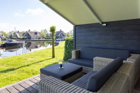 Terrasse couverte du chalet Water park Terkaple 1 aux Pays-Bas, vue sur le canal et le jardin.