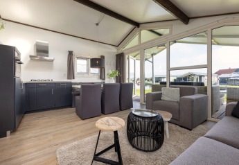 Bright, modern living space at Water park Terkaple 1 chalet in the Netherlands with large windows and sofa.