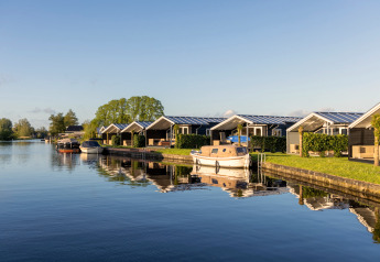 Chalets aan het water bij Water park Terkaple 1 in Nederland met boten aangemeerd aan de kade.