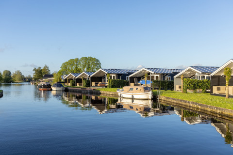 Chalets am Wasser im Water park Terkaple 1 in den Niederlanden mit Booten am Ufer vertäut.