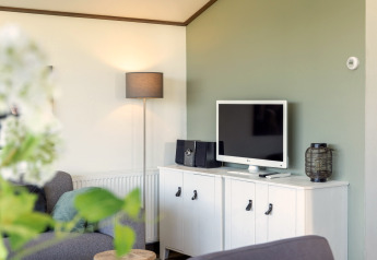 Woonkamer in chalet Water park «Terkaple 1» in Nederland met TV, grijze zetel en witte kast.