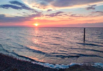 Splendido tramonto sull'acqua vicino alla riva presso lo chalet Water park «Terkaple 1» nei Paesi Bassi.