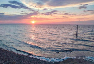 Magnifique coucher de soleil sur l’eau près du rivage au chalet Water park «Terkaple 1» aux Pays-Bas.