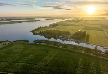 Luchtfoto van Water park Terkaple 1 in Nederland met water, groene weilanden en zonsopgang.
