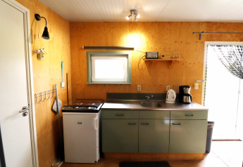 Pequeña cocina acogedora en Cosy cabin 1, Países Bajos, con estufa, fregadero y cafetera.