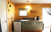 Kleine, gezellige keuken in Cosy cabin 1 in Nederland, met fornuis, koelkast, gootsteen en koffiezetapparaat.