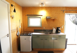 Petite cuisine chaleureuse dans Cosy cabin 1 aux Pays-Bas avec réfrigérateur, évier et cafetière.