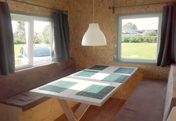 Eethoek in een knusse hut met ramen, bruine banken en een witte tafel in Nederland.
