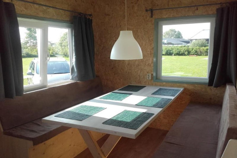 Coin repas dans une cabane douillette avec bancs marron, table blanche et fenêtres aux Pays-Bas.