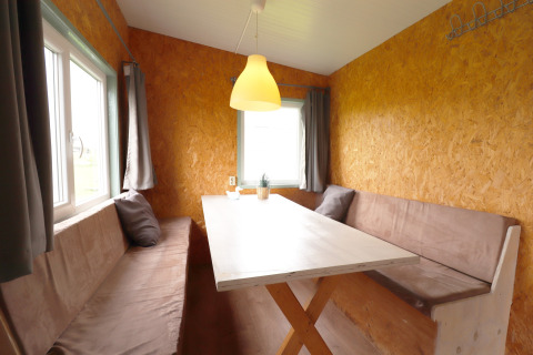 Coin repas avec bancs et table en bois dans la Cosy cabin 1, Pays-Bas, avec murs brun clair.