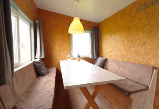 Coin repas avec bancs et table en bois dans la Cosy cabin 1, Pays-Bas, avec murs brun clair.
