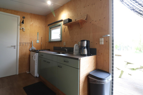 Petite cuisine de lodge en bois clair avec évier, cafetière et fenêtre à Cosy cabin 1, Pays-Bas.