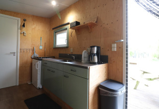 Petite cuisine de lodge en bois clair avec évier, cafetière et fenêtre à Cosy cabin 1, Pays-Bas.